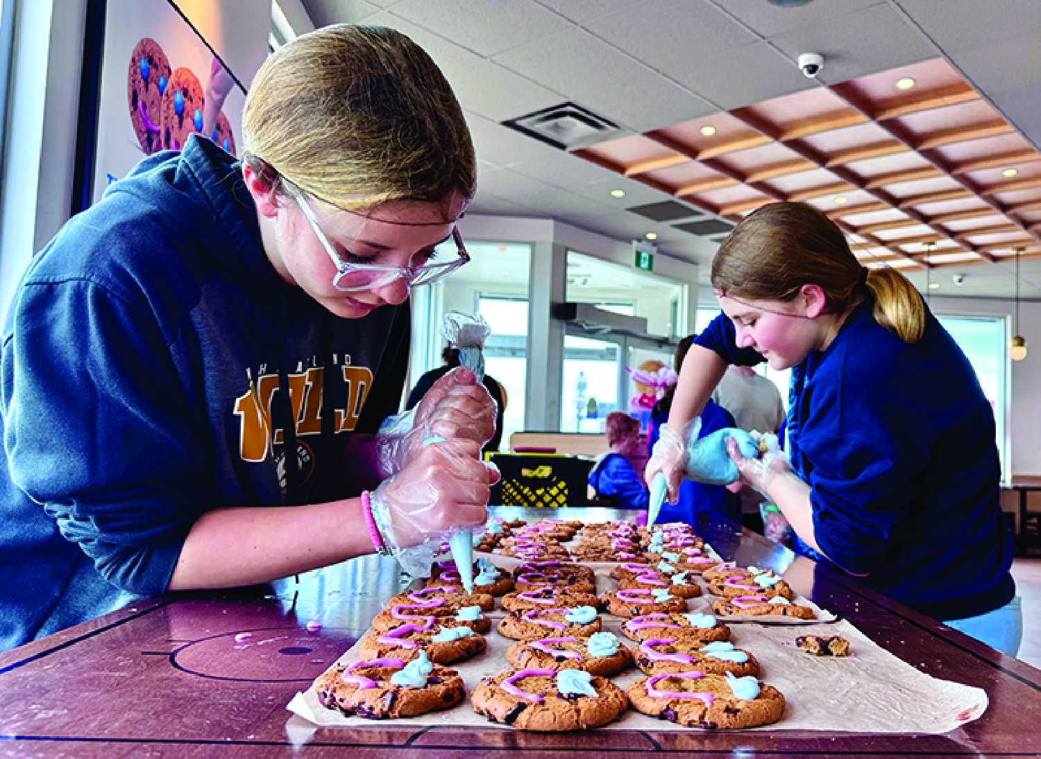 McNaughton High Grade 6 students Aubree Easton and Blakeley Hintz decorating Smile Cookies during Moosomin’s Smile Cookie Week.